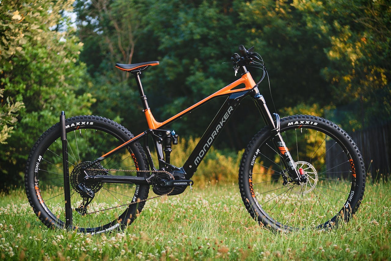 High-quality image of a mountain bike parked in a grassy area surrounded by trees.